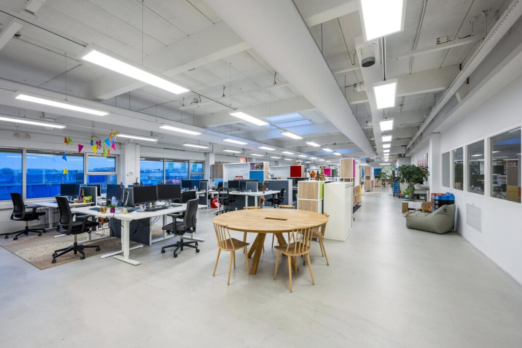 Modern en ruim kantoorinterieur aan de Van der Madeweg met werkplekken, ronde vergadertafel en kleurrijke details.